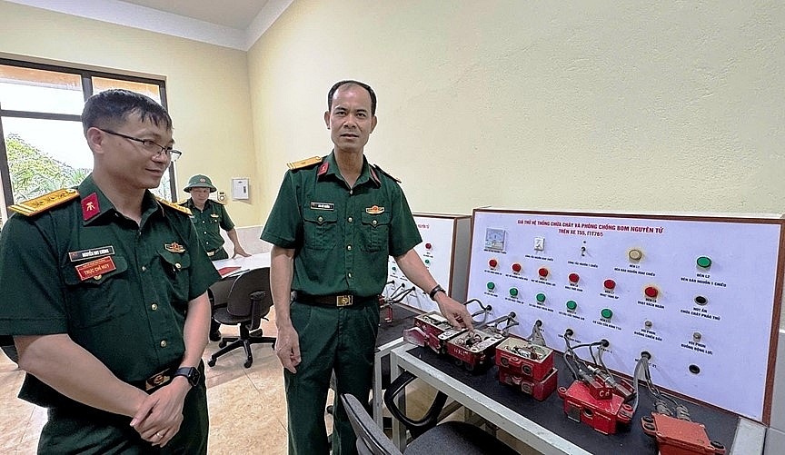 Thiếu tá quân nhân chuyên nghiệp Bùi Đức Ngừng giới thiệu với Thượng tá Nguyễn Huy Cương, Giám đốc Xưởng X1 về sáng kiến “Giá thử hệ thống chữa cháy và phòng, chống bom nguyên tử trên xe T-55 và PT-76B”. Ảnh: THÁI KIÊN Thiếu tá quân nhân chuyên nghiệp Bùi Đức Ngừng giới thiệu với Thượng tá Nguyễn Huy Cương, Giám đốc Xưởng X1 về sáng kiến “Giá thử hệ thống chữa cháy và phòng, chống bom nguyên tử trên xe T-55 và PT-76B”. Ảnh: THÁI KIÊN